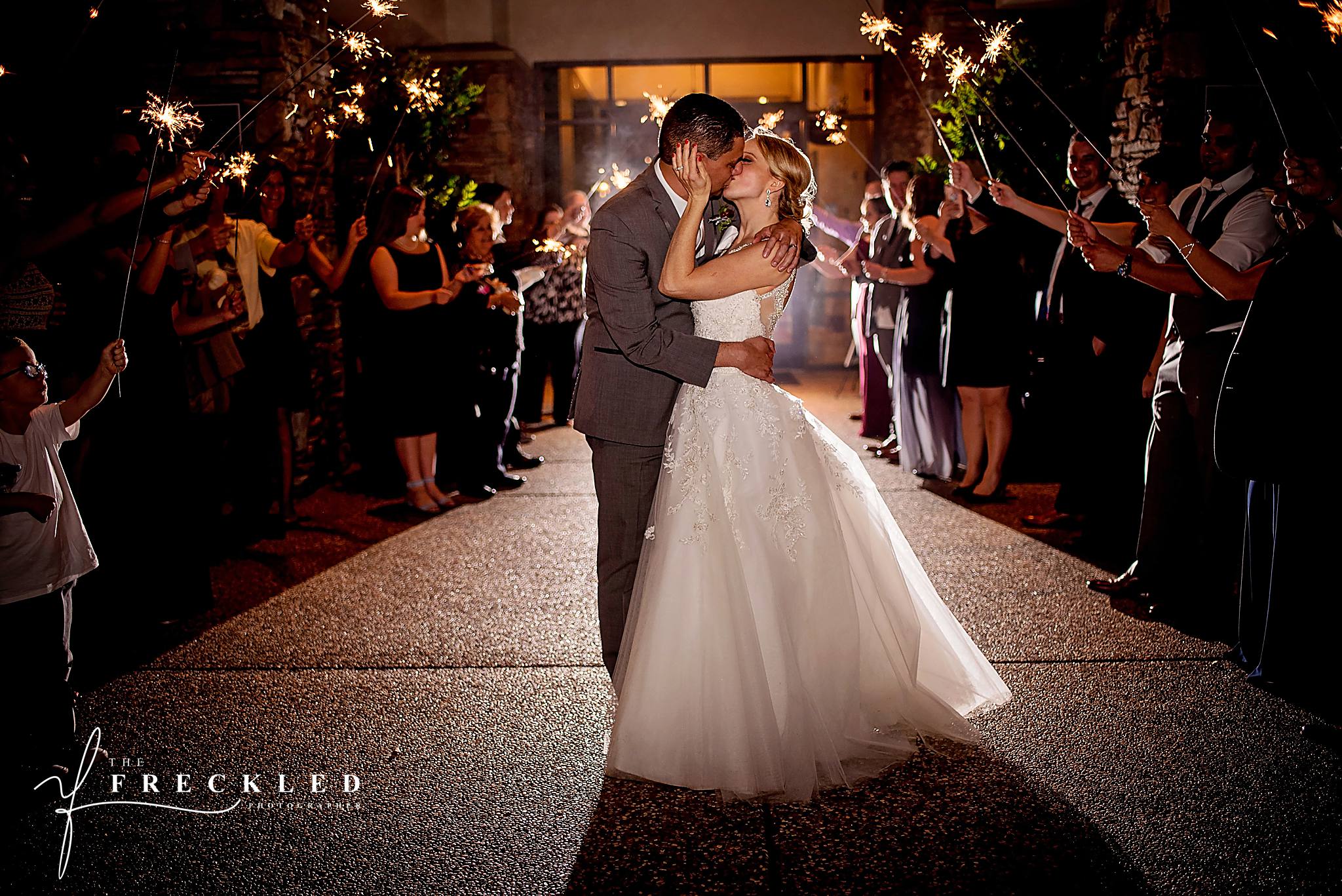 bride and groom embrace in a kiss during their wedding sparkler exit