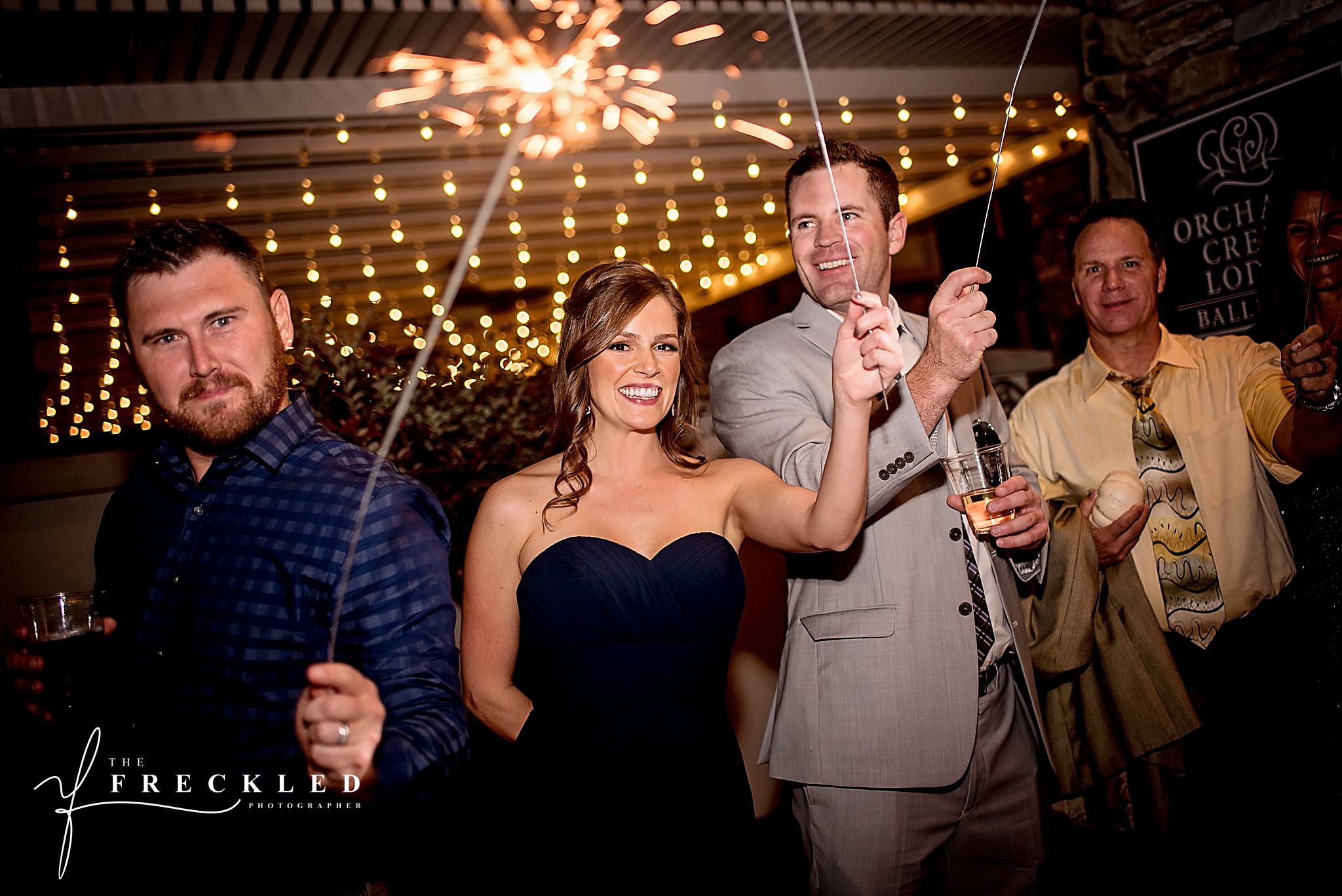 guests smiling as they hold sparklers waiting for bride and groom