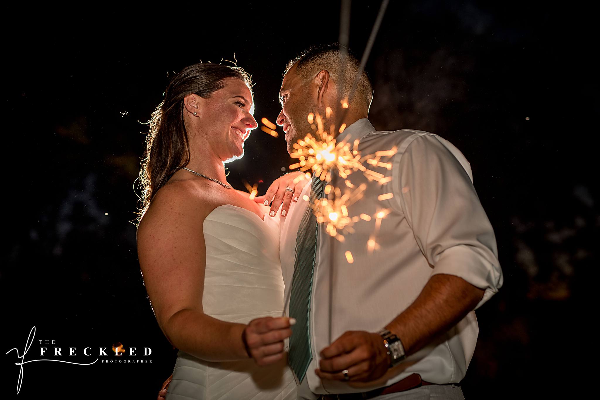 close-up portrait of married couple holding sparklers at the wedding